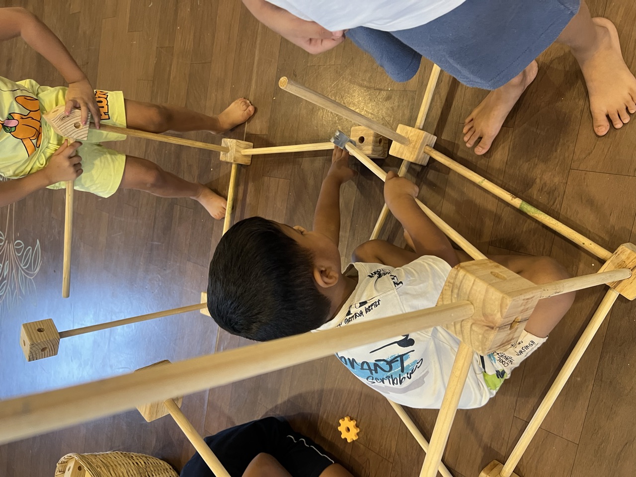 Children building a large structure from wooden dowels and notched blocks